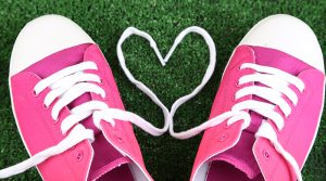 Pink running shoes with the laces formed into a heart shape.