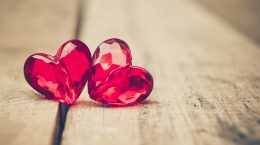 Two heart-shaped red beads standing side by side.