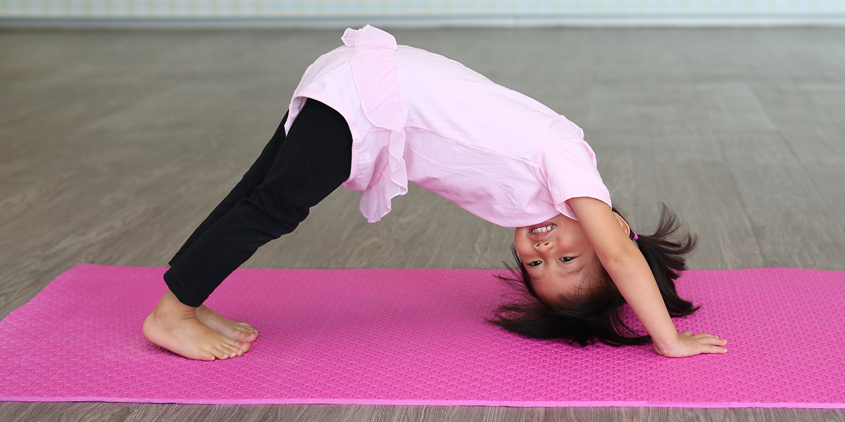 A toddler doing a headstand with their feet on the ground.