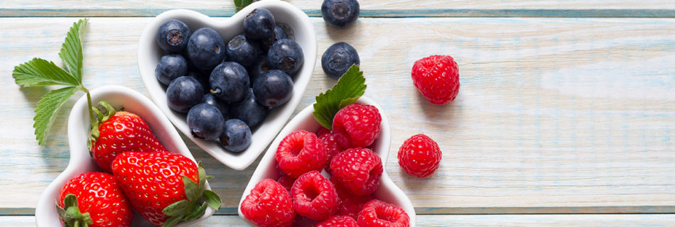 Small heart-shaped bowls with strawberries, blueberries, and raspberries