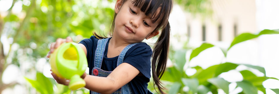 A child waters several plants in small pots